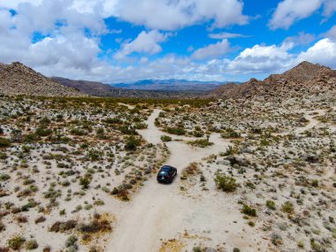 Çölde yoldan giden 4x4'lük otomobilin havadan görünümü. Joshua Tree Milli Parkı. Güneydoğu Kaliforniya'daki Amerikan Milli Parkı. Kurak çölde SUV sürüş.