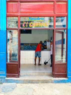 Eski Havana, Küba'nın merkezinde küçük bir fırın dükkanı. Fırından ekmek alan adam. Küçük fırının renkli cephesi.  