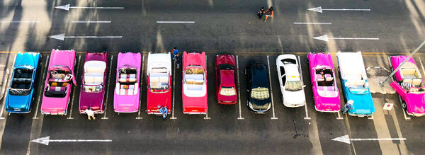 Классические автомобили в различных цветах, выстроились в ряд в парке Централ в Гаване, Куба. Группа красочных старинных автомобилей такси, припаркованных в Старой Гаване
. 