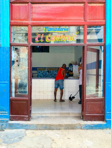 Eski Havana, Küba'nın merkezinde küçük bir fırın dükkanı. Fırından ekmek alan adam. Küçük fırının renkli cephesi.  