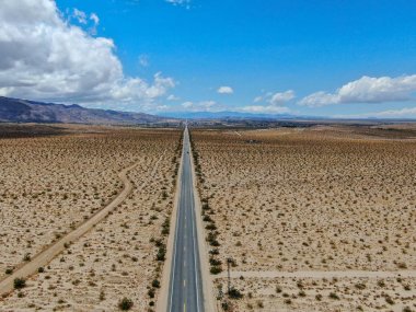 Joshua Tree Park'ın yanındaki uçsuz bucaksız çöl düz yolunun havadan görünümü. Abd. Arizona yönüne doğru çöle doğru giden uzun düz asfalt yol.