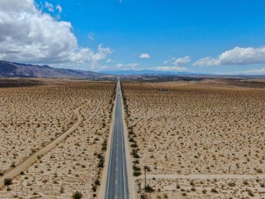 Joshua Tree Park'ın yanındaki uçsuz bucaksız çöl düz yolunun havadan görünümü. Abd. Arizona yönüne doğru çöle doğru giden uzun düz asfalt yol.