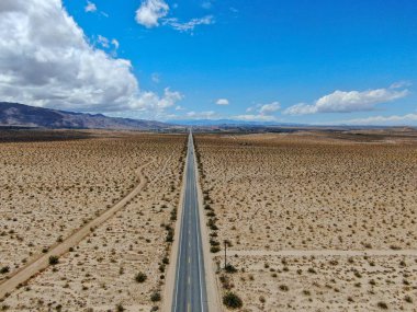 Joshua Tree Park'ın yanındaki uçsuz bucaksız çöl düz yolunun havadan görünümü. Abd. Arizona yönüne doğru çöle doğru giden uzun düz asfalt yol.