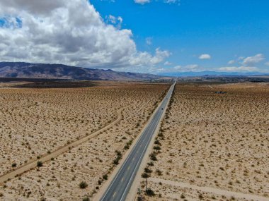 Joshua Tree Park'ın yanındaki uçsuz bucaksız çöl düz yolunun havadan görünümü. Abd. Arizona yönüne doğru çöle doğru giden uzun düz asfalt yol.
