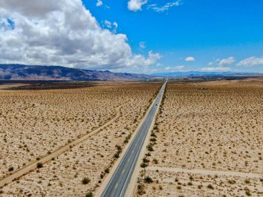 Joshua Tree Park'ın yanındaki uçsuz bucaksız çöl düz yolunun havadan görünümü. Abd. Arizona yönüne doğru çöle doğru giden uzun düz asfalt yol.