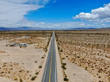 Joshua Tree Park'ın yanındaki uçsuz bucaksız çöl düz yolunun havadan görünümü. Abd. Arizona yönüne doğru çöle doğru giden uzun düz asfalt yol.