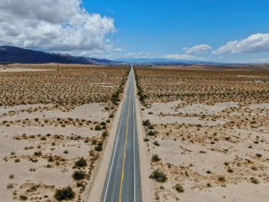 Joshua Tree Park'ın yanındaki uçsuz bucaksız çöl düz yolunun havadan görünümü. Abd. Arizona yönüne doğru çöle doğru giden uzun düz asfalt yol.