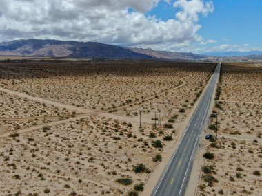 Joshua Tree Park'ın yanındaki uçsuz bucaksız çöl düz yolunun havadan görünümü. Abd. Arizona yönüne doğru çöle doğru giden uzun düz asfalt yol.