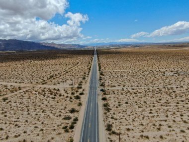 Joshua Tree Park'ın yanındaki uçsuz bucaksız çöl düz yolunun havadan görünümü. Abd. Arizona yönüne doğru çöle doğru giden uzun düz asfalt yol.
