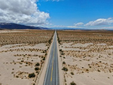 Joshua Tree Park'ın yanındaki uçsuz bucaksız çöl düz yolunun havadan görünümü. Abd. Arizona yönüne doğru çöle doğru giden uzun düz asfalt yol.