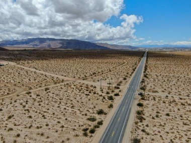 Joshua Tree Park'ın yanındaki uçsuz bucaksız çöl düz yolunun havadan görünümü. Abd. Arizona yönüne doğru çöle doğru giden uzun düz asfalt yol.