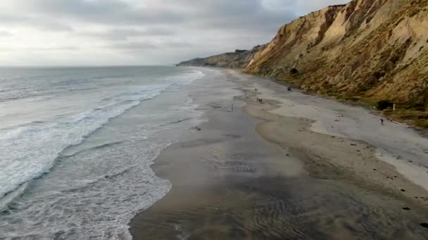 黄色い砂岩の崖と波が日没時にビーチを急いで太平洋の海岸線の航空写真 ブラックビーチ トーリーパインズ州自然保護区 サンディエゴ カリフォルニア アメリカ — ストック動画