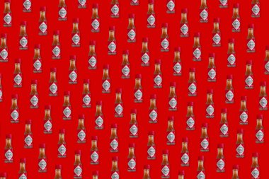 Tabasco Chili Pepper Sos Mini şişe yapılmış Yaratıcı desen. Kırmızı renkli arka plan üzerinde Tabasco Chili Pepper Sauce şişe üst görünümü.
