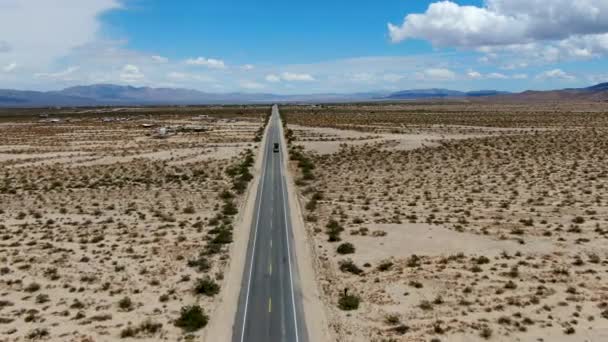 ジョシュアツリーパークの隣の無限の砂漠のまっすぐな道の航空写真 アリゾナ方面に砂漠に向かう長いまっすぐなターマック道路 — ストック動画