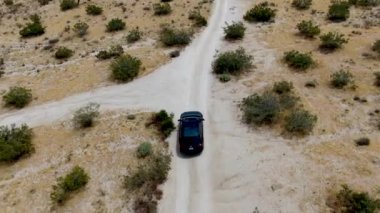 Çölde yoldan giden 4x4'lük otomobilin havadan görünümü. Joshua Tree Milli Parkı. Güneydoğu Kaliforniya'daki Amerikan Milli Parkı. Kurak çölde SUV sürüş.