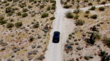 Çölde yoldan giden 4x4'lük otomobilin havadan görünümü. Joshua Tree Milli Parkı. Güneydoğu Kaliforniya'daki Amerikan Milli Parkı. Kurak çölde SUV sürüş.