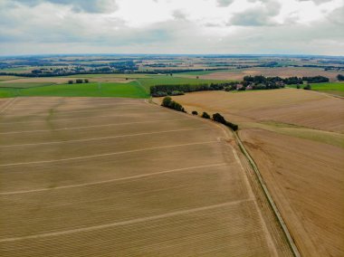 Walloon, Belçika'da kırsal bölge havadan görünümü, bulutlu bir gün boyunca ağaçla çevrili kuru kurak tarım arazileri