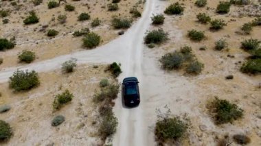 Çölde yoldan giden 4x4'lük otomobilin havadan görünümü. Joshua Tree Milli Parkı. Güneydoğu Kaliforniya'daki Amerikan Milli Parkı. Kurak çölde suv sürüyor. California, Amerika Birleşik Devletleri