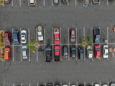 Renkli araç çeşitleri ile süpermarkette otopark havadan üst görünümü. İnsanlar arabalarına yürüyüp park etmeye çalışıyor..