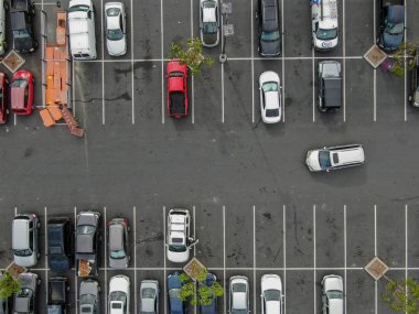 Renkli araç çeşitleri ile süpermarkette otopark havadan üst görünümü. İnsanlar arabalarına yürüyüp park etmeye çalışıyor..