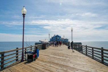 Fisher, mavi yaz günü, Oceanside, Kuzey San Diego County, Kaliforniya sırasında Oceanside Iskelesi 'nde balık yakalamak için çalışıyor. Batı Amerika Birleşik Devletleri kıyı şeridinde ahşap iskele.