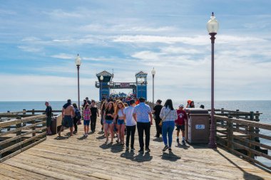 Mavi yaz gününde Oceanside İskelesi'nde yürüyen turist, Oceanside, kuzey San Diego County, Kaliforniya. Batı Amerika Birleşik Devletleri kıyı şeridinde ahşap iskele. Balıkçı ile ünlüdür. 
