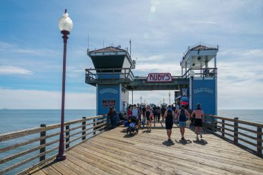 Mavi yaz gününde Oceanside İskelesi'nde yürüyen turist, Oceanside, kuzey San Diego County, Kaliforniya. Batı Amerika Birleşik Devletleri kıyı şeridinde ahşap iskele. Balıkçı ile ünlüdür. 