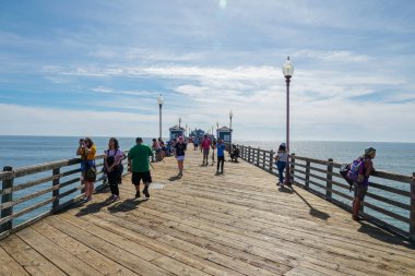 Mavi yaz gününde Oceanside İskelesi'nde yürüyen turist, Oceanside, kuzey San Diego County, Kaliforniya. Batı Amerika Birleşik Devletleri kıyı şeridinde ahşap iskele. Balıkçı ile ünlüdür. 