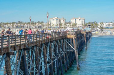 Mavi yaz gününde Oceanside İskelesi'nde yürüyen turist, Oceanside, kuzey San Diego County, Kaliforniya. Batı Amerika Birleşik Devletleri kıyı şeridinde ahşap iskele. Balıkçı ile ünlüdür. 