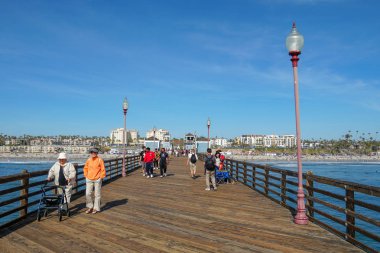 Mavi yaz gününde Oceanside İskelesi'nde yürüyen turist, Oceanside, kuzey San Diego County, Kaliforniya. Batı Amerika Birleşik Devletleri kıyı şeridinde ahşap iskele. Balıkçı ile ünlüdür. 