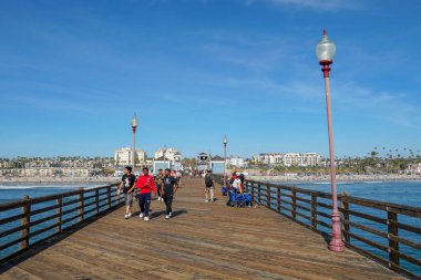 Mavi yaz gününde Oceanside İskelesi'nde yürüyen turist, Oceanside, kuzey San Diego County, Kaliforniya. Batı Amerika Birleşik Devletleri kıyı şeridinde ahşap iskele. Balıkçı ile ünlüdür. 