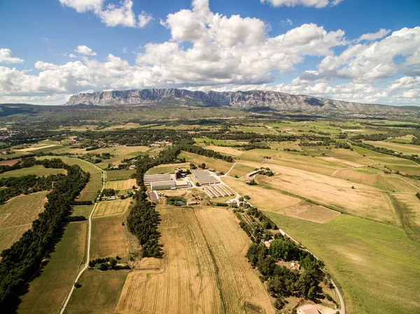Aerial view of farm field with big farm in  South of France. Big farm land during summer dry season next the mountain.