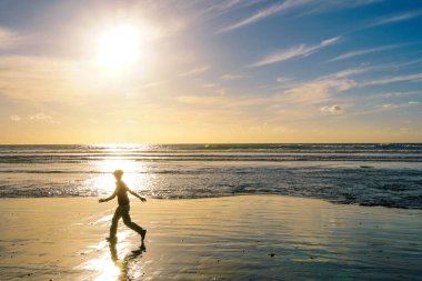 Gün batımı huzurlu an sırasında zevk ve yürüyüş insanların silüeti. Alacakaranlık zaman ve deniz üzerinde yansıma güzel gökyüzü.