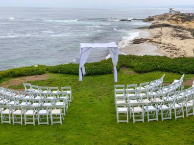 Okyanus önünde bahçede beyaz sandalyeler ve kemer ile düğün töreni ayarı, düğün konsepti, La Jolla, Kaliforniya, ABD