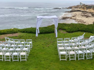 Okyanus önünde bahçede beyaz sandalyeler ve kemer ile düğün töreni ayarı, düğün konsepti, La Jolla, Kaliforniya, ABD