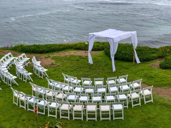 Wedding ceremony setting  with white chairs and arch in the garden in front of the ocean, wedding concept, La Jolla, California, USA