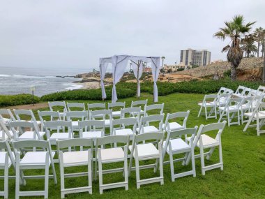 Okyanus önünde bahçede beyaz sandalyeler ve kemer ile düğün töreni ayarı, düğün konsepti, La Jolla, Kaliforniya, ABD