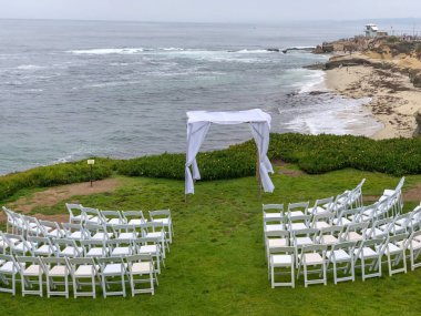 Okyanus önünde bahçede beyaz sandalyeler ve kemer ile düğün töreni ayarı, düğün konsepti, La Jolla, Kaliforniya, ABD