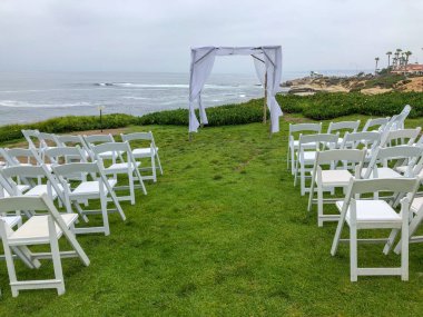 Okyanus önünde bahçede beyaz sandalyeler ve kemer ile düğün töreni ayarı, düğün konsepti, La Jolla, Kaliforniya, ABD