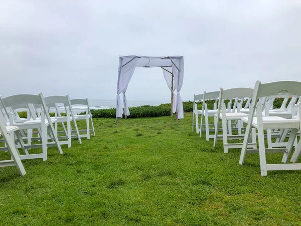 Wedding ceremony setting  with white chairs and arch in the garden in front of the ocean, wedding concept, La Jolla, California, USA