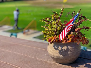 Amerikan bayrakları ve arka planda golfçü ile Vatansever çiçek saksı. Amerikan bayrağı dekorasyonu.