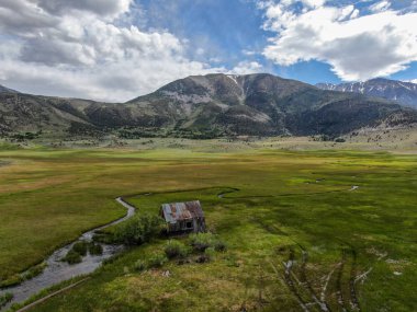 Bir dağın yeşil vadisinde terk edilmiş küçük ahşap ev ahır sonraki küçük nehir havadan görünümü, Aspen Spring, mono County, Kaliforniya, ABD. 