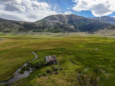 Bir dağın yeşil vadisinde terk edilmiş küçük ahşap ev ahır sonraki küçük nehir havadan görünümü, Aspen Spring, mono County, Kaliforniya, ABD. 