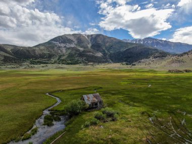 Bir dağın yeşil vadisinde terk edilmiş küçük ahşap ev ahır sonraki küçük nehir havadan görünümü, Aspen Spring, mono County, Kaliforniya, ABD. 