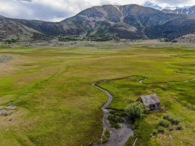 Bir dağın yeşil vadisinde terk edilmiş küçük ahşap ev ahır sonraki küçük nehir havadan görünümü, Aspen Spring, mono County, Kaliforniya, ABD. 