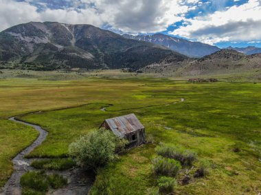 Bir dağın yeşil vadisinde terk edilmiş küçük ahşap ev ahır sonraki küçük nehir havadan görünümü, Aspen Spring, mono County, Kaliforniya, ABD. 