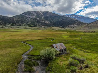 Bir dağın yeşil vadisinde terk edilmiş küçük ahşap ev ahır sonraki küçük nehir havadan görünümü, Aspen Spring, mono County, Kaliforniya, ABD. 