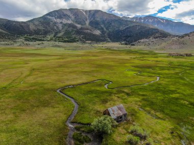 Bir dağın yeşil vadisinde terk edilmiş küçük ahşap ev ahır sonraki küçük nehir havadan görünümü, Aspen Spring, mono County, Kaliforniya, ABD. 