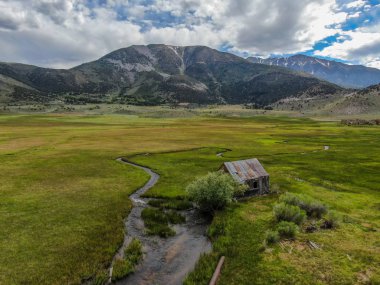 Bir dağın yeşil vadisinde terk edilmiş küçük ahşap ev ahır sonraki küçük nehir havadan görünümü, Aspen Spring, mono County, Kaliforniya, ABD. 
