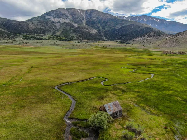 Bir dağın yeşil vadisinde terk edilmiş küçük ahşap ev ahır sonraki küçük nehir havadan görünümü, Aspen Spring, mono County, Kaliforniya, ABD. 